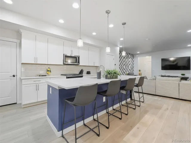 a kitchen with a dining table chairs a sink and a refrigerator