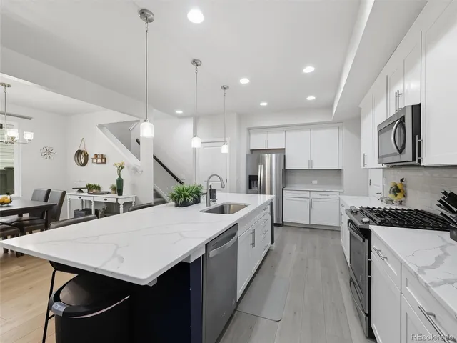 a kitchen with a stove a refrigerator a sink and chairs