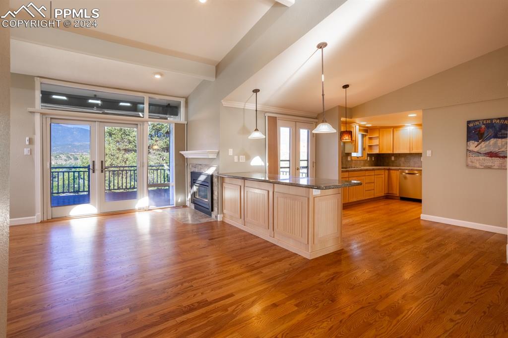 1074 Fontmore Road, Unit C Colorado Springs, CO 80904 - Photo 5 of 30 Living room featuring light brown cabinetry, light hardwood / wood-style flooring, vaulted ceiling, large window and fireplace
