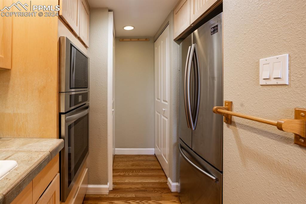 1074 Fontmore Road, Unit C Colorado Springs, CO 80904 - Photo 10 of 30 Kitchen appliances with stainless steel finishes, tile counters, light brown cabinets, and dark wood-type flooring
