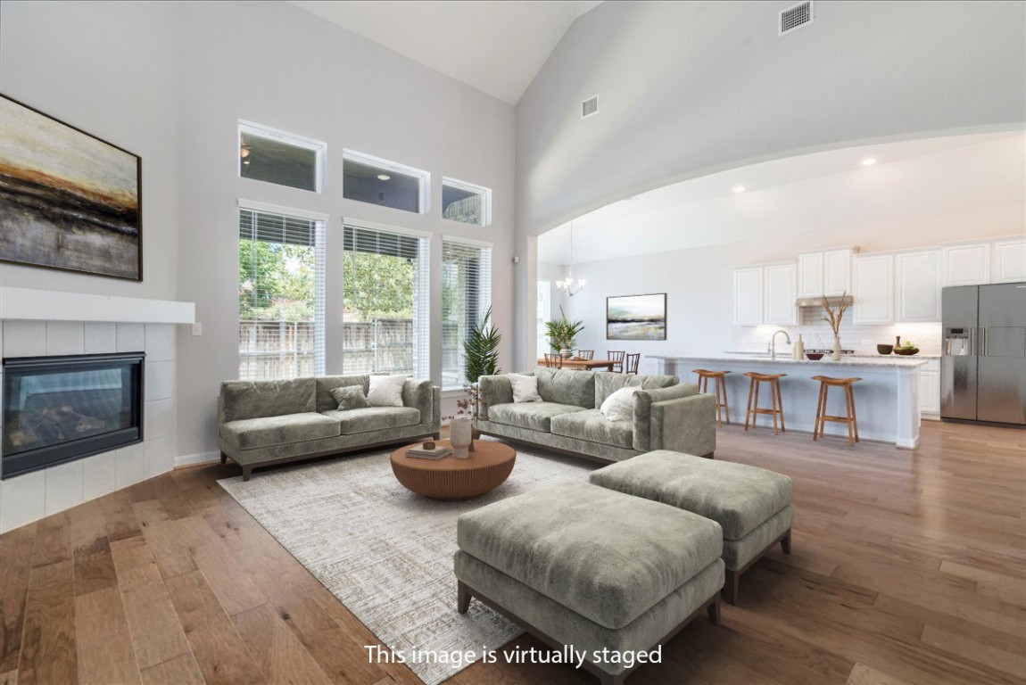 584 Baretta Loop Buda, TX 78610 - Photo 12 of 37 Living room with a chandelier, high vaulted ceiling, light wood-type flooring, and a fireplace