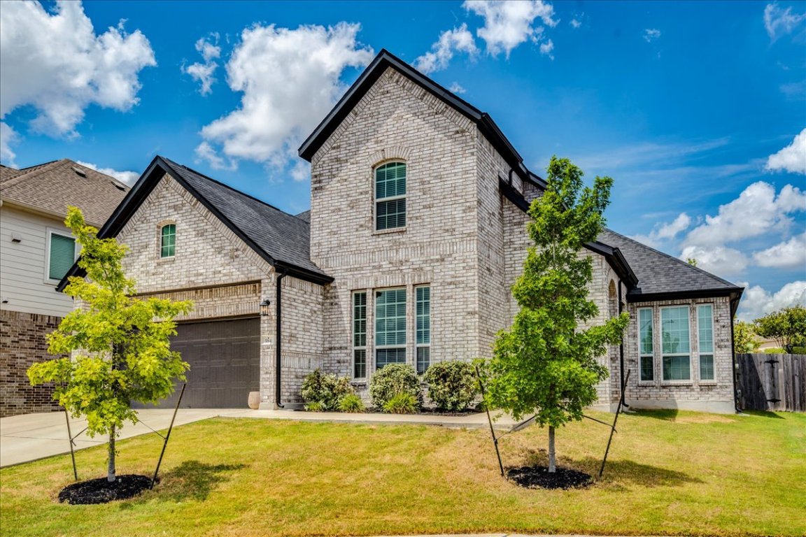 584 Baretta Loop Buda, TX 78610 - Photo 34 of 37 French country home with brick siding, concrete driveway, a front yard, and an attached garage