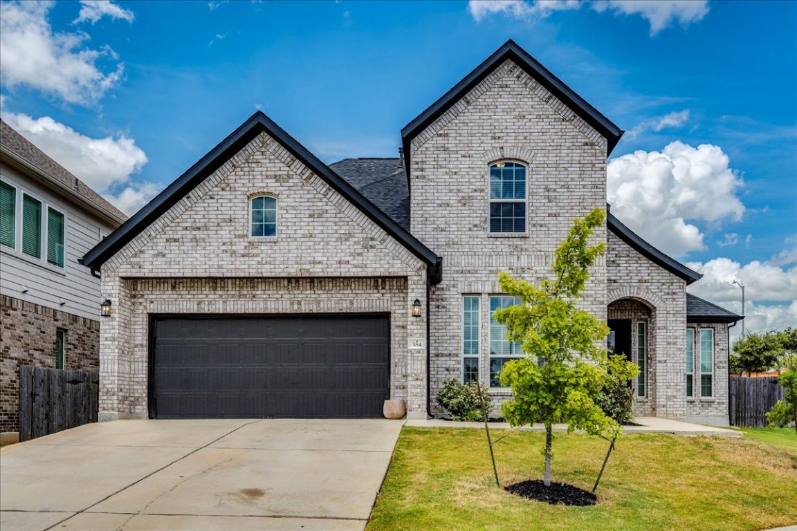 584 Baretta Loop Buda, TX 78610 - Photo 5 of 37 French country inspired facade with brick siding, driveway, and a garage