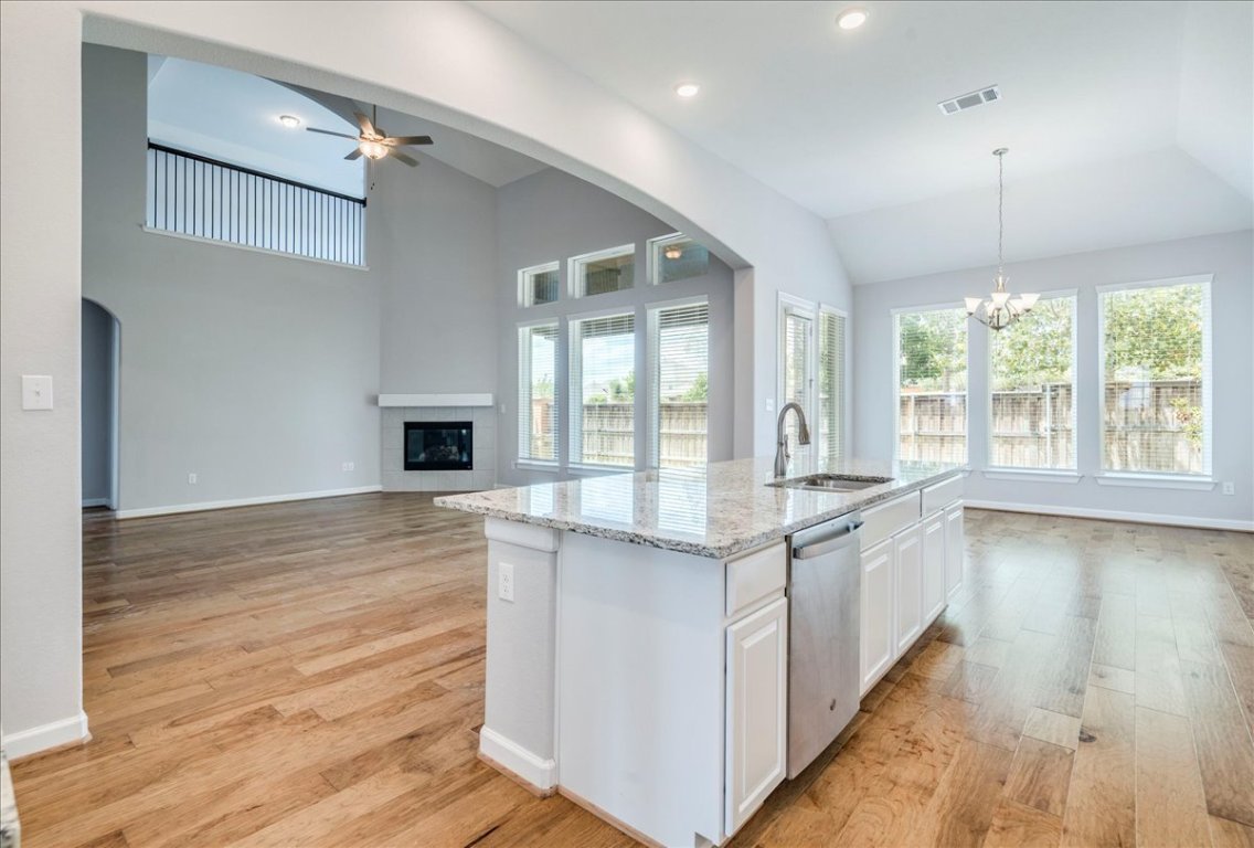 584 Baretta Loop Buda, TX 78610 - Photo 37 of 37 Kitchen with arched walkways, white cabinetry, light wood finished floors, light stone countertops, and open floor plan