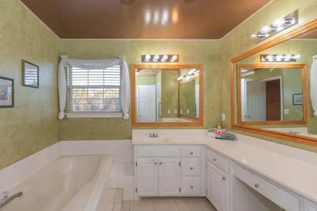 a bathroom with a sink mirror and a bathtub next to a window