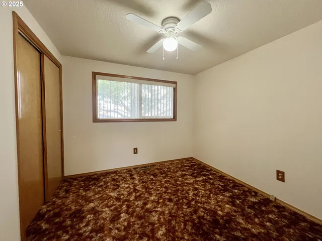 a view of a big room with windows and chandelier fan