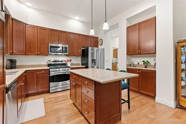 a kitchen with kitchen island granite countertop stainless steel appliances and wooden cabinets