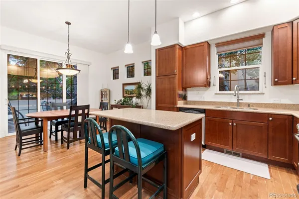 a kitchen with stainless steel appliances granite countertop a stove a refrigerator a sink a dining table and chairs with wooden floor