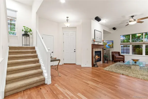 a view of a livingroom with furniture wooden floor fireplace and windows