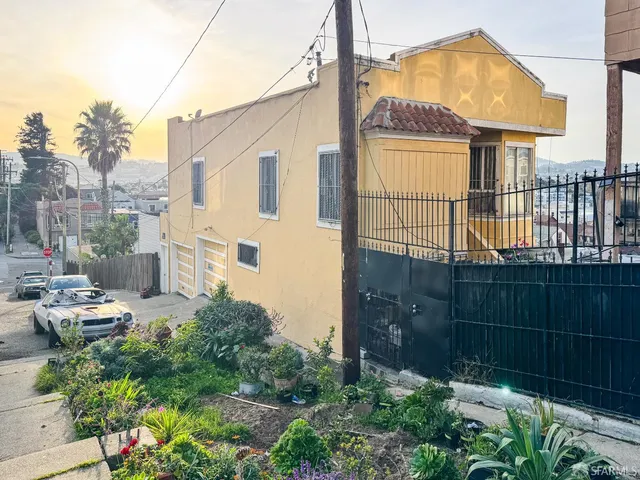 a backyard of a house with a fountain plants and large tree