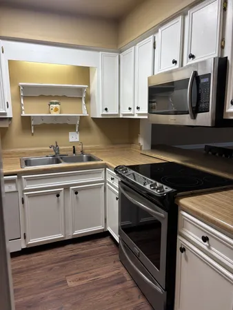 a kitchen with stainless steel appliances white cabinets granite counter tops and a window
