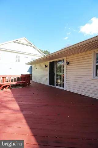 a porch with wooden floor in front of it with yard
