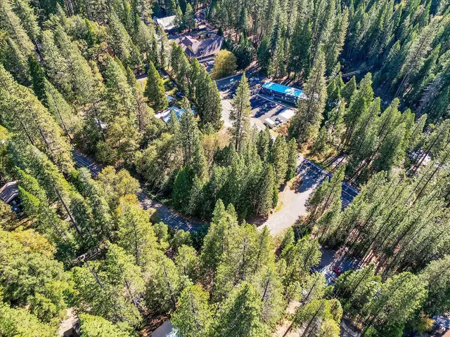 an aerial view of residential house with outdoor space and trees all around