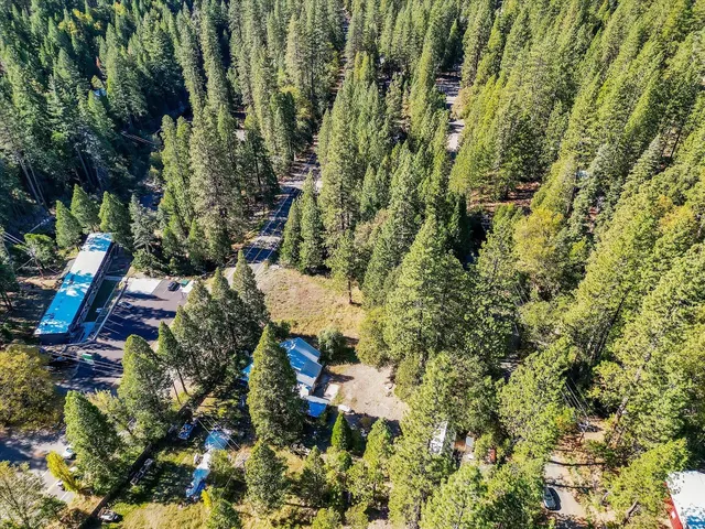 an aerial view of residential house with outdoor space and trees all around