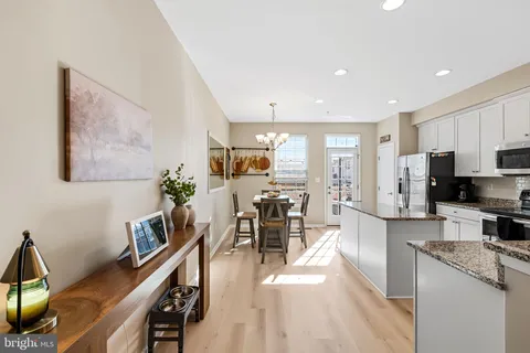 a kitchen with stainless steel appliances kitchen island granite countertop a refrigerator a stove a sink a dining table and chairs with wooden floor