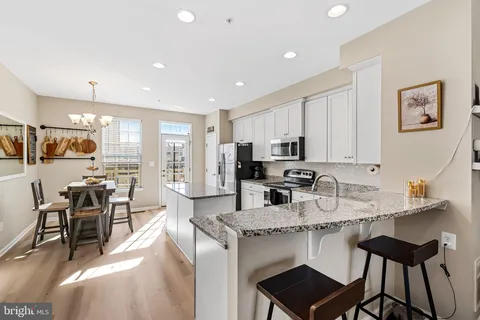 a kitchen with stainless steel appliances granite countertop a stove a sink a microwave a dining table and chairs