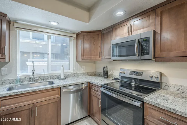 a kitchen with stainless steel appliances granite countertop a sink a stove a microwave and cabinets