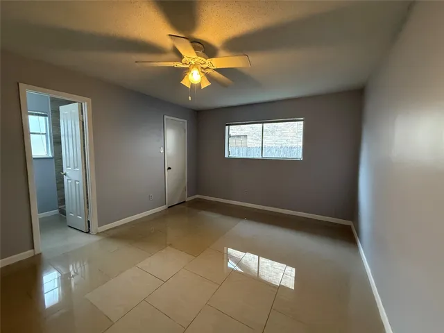 an empty room with windows and fan
