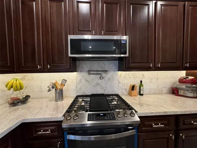 a kitchen with granite countertop a sink stainless steel appliances and cabinets