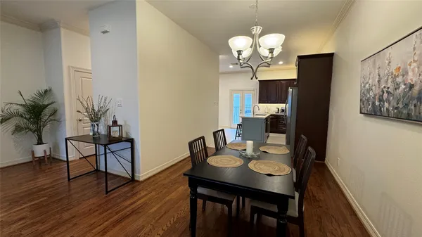 a dining room with wooden floor a chandelier a wooden table and chairs