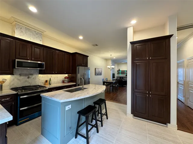 a kitchen with kitchen island granite countertop a sink a stove a refrigerator and cabinets