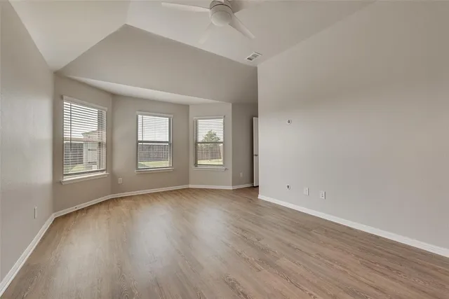 an empty room with wooden floor and ceiling fan