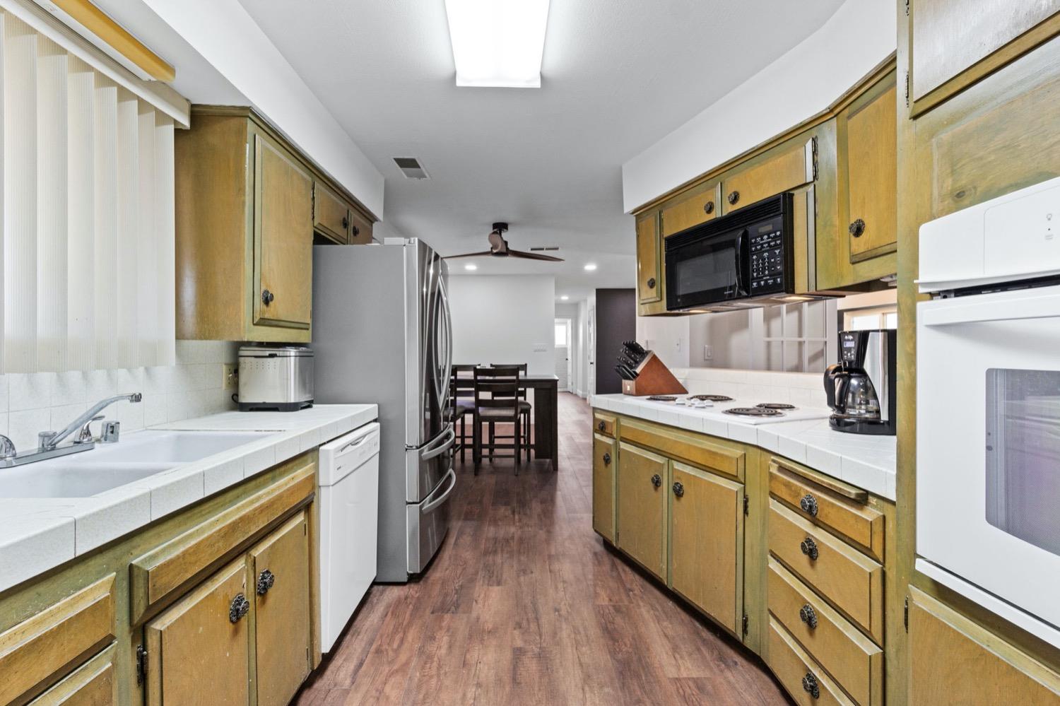 5654 North 7th Street Fresno, CA 93710 - Photo 11 of 38 a large kitchen with stainless steel appliances a stove a sink dishwasher a microwave oven and a dining table with wooden floor