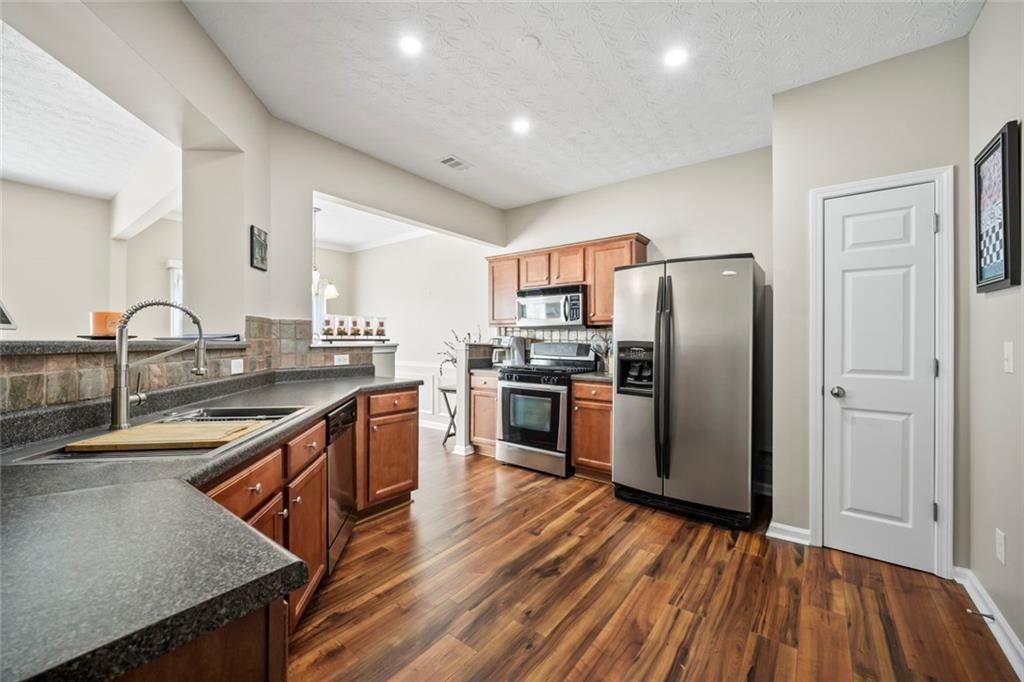 6066 Allpoint Way Fairburn, GA 30213 - Photo 16 of 43 a kitchen with stainless steel appliances granite countertop a refrigerator a sink dishwasher a stove with wooden floors and cabinets