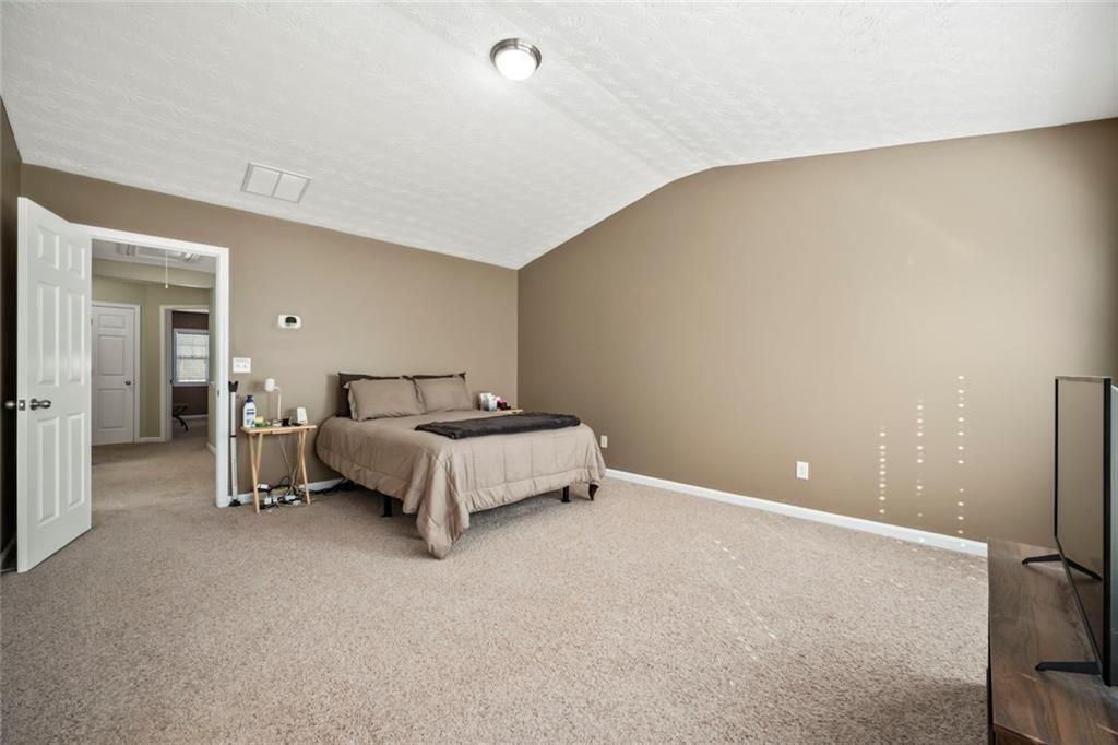 6066 Allpoint Way Fairburn, GA 30213 - Photo 20 of 43 a spacious bedroom with a bed and a lamp on the table