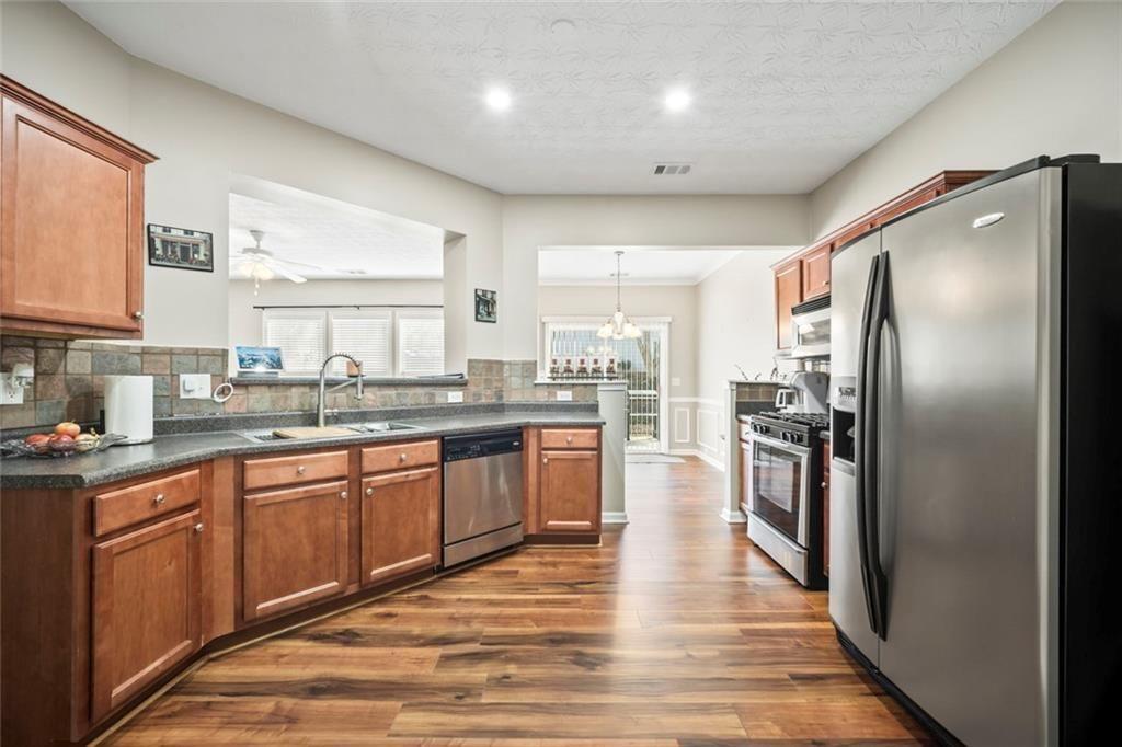 6066 Allpoint Way Fairburn, GA 30213 - Photo 3 of 43 a large kitchen with stainless steel appliances granite countertop a refrigerator a sink dishwasher a stove with wooden cabinets and floor