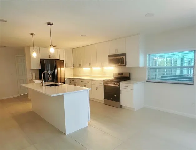 a kitchen with kitchen island a counter top a stove a sink and a refrigerator