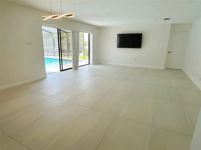 a view of an empty room with a window and a flat screen tv