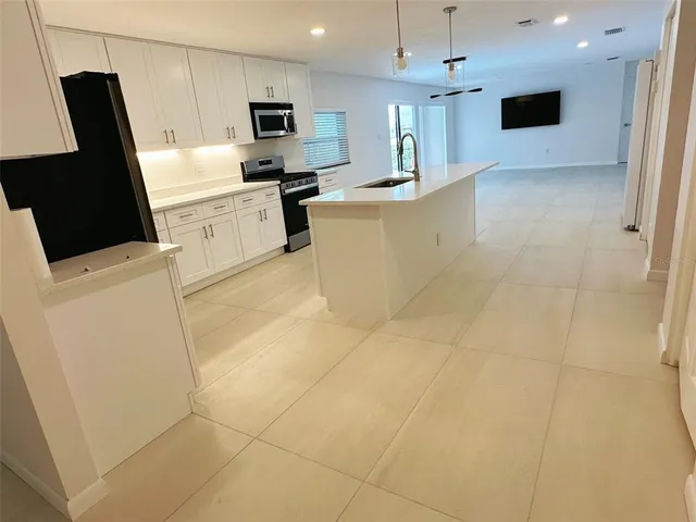 a kitchen with stainless steel appliances a refrigerator a sink a stove top oven a counter space and cabinets