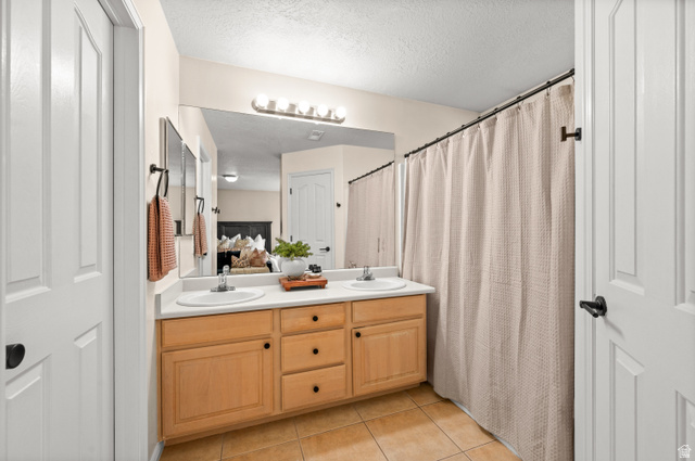 174 Rockey Park Lane, Unit 34 Draper, UT 84020 - Photo 12 of 20 Bathroom with double vanity, light tile patterned floors, curtained shower, and a textured ceiling