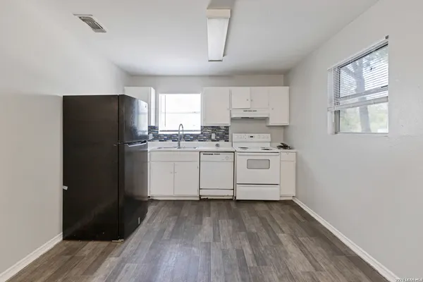 a kitchen with a white cabinets and wooden floor