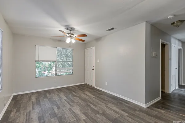 a view of an empty room with wooden floor and a window