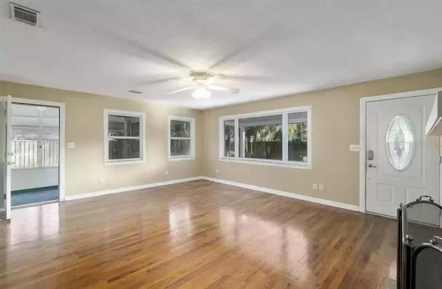 an empty room with wooden floor and windows
