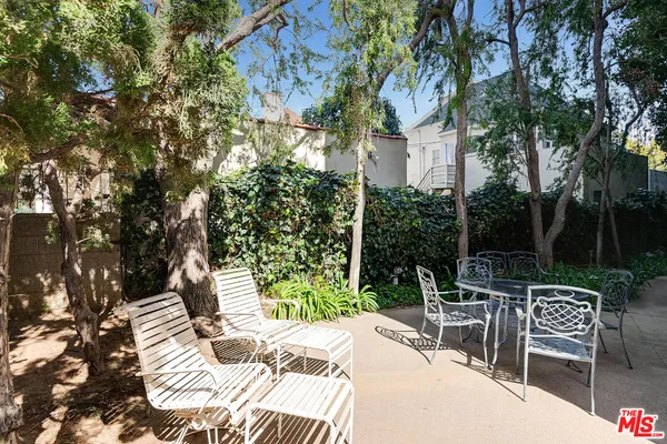 a view of a patio with table and chairs and potted plants with large tree