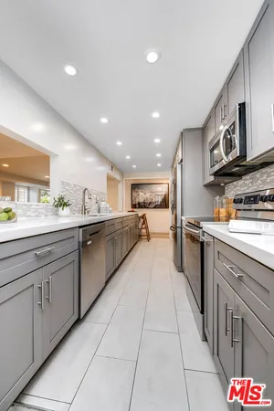 a large white kitchen with stainless steel appliances granite countertop lots of counter top space and cabinets