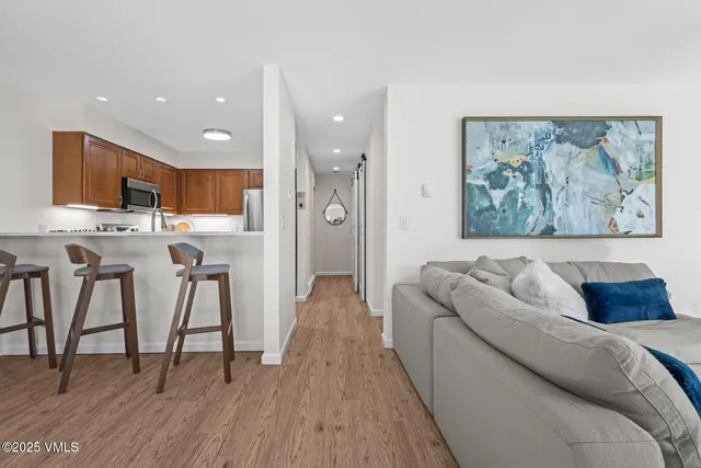 a living room with stainless steel appliances furniture and a kitchen view