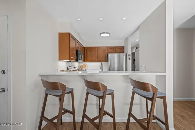 a kitchen with stainless steel appliances granite countertop a table chairs sink and cabinets