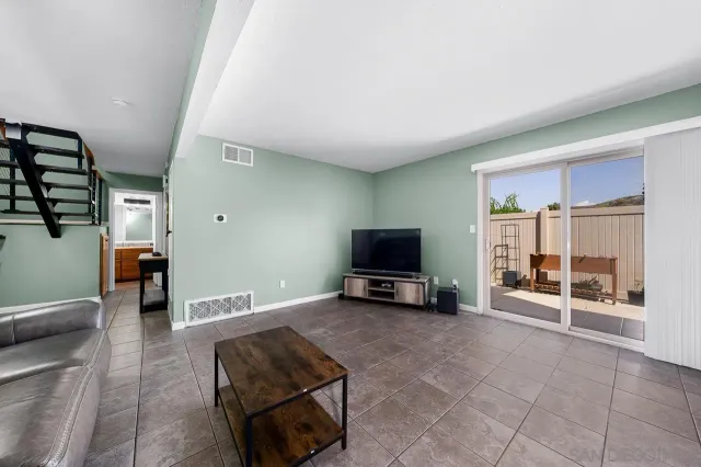 a living room with furniture a flat screen tv and glass door