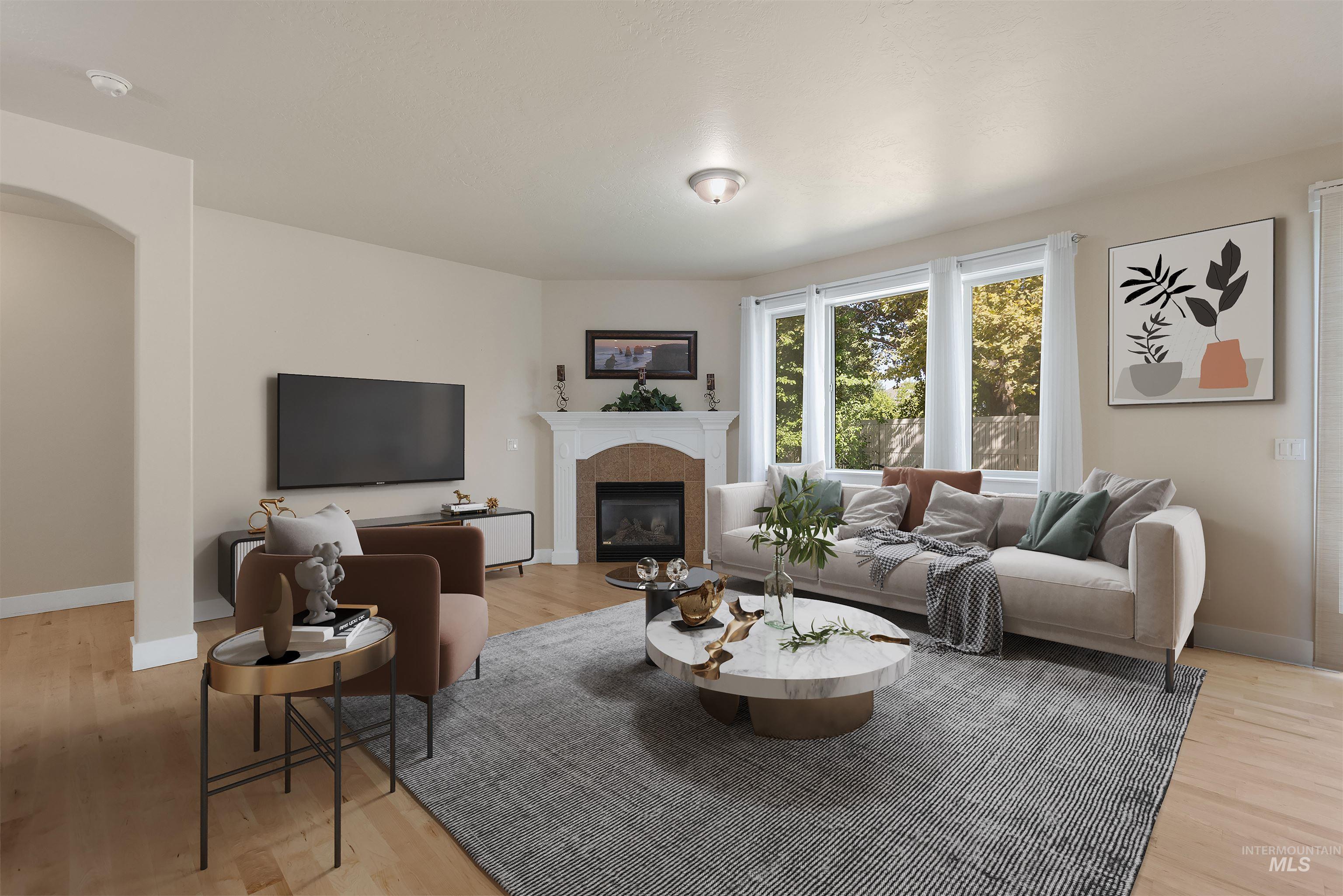1838 West Pachino Street Meridian, ID 83646 - Photo 4 of 34 Living room featuring light wood finished floors, a fireplace, and arched walkways