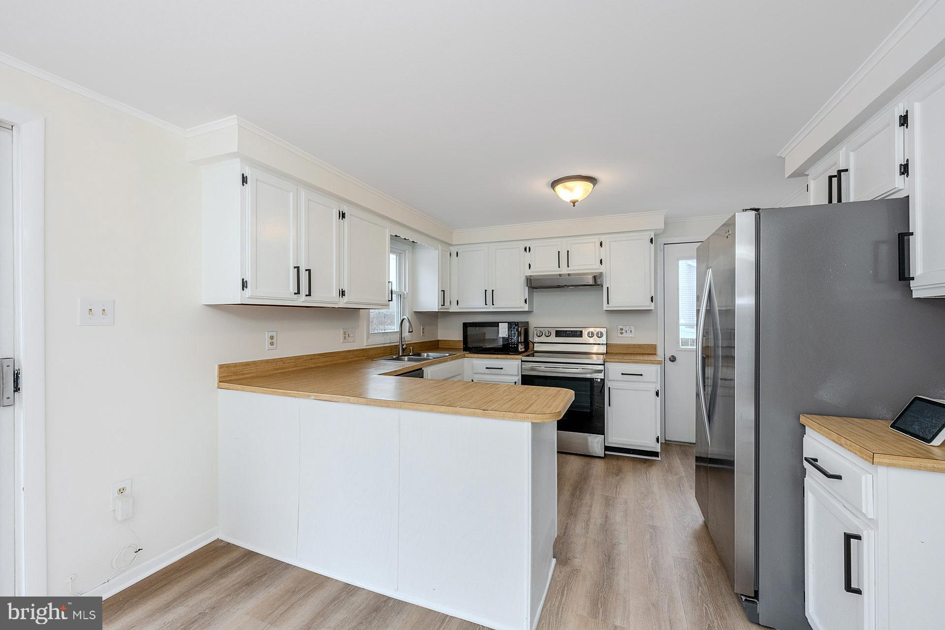 8414 Belding Court Brandywine, MD 20613 - Photo 13 of 37 a kitchen with stainless steel appliances granite countertop a refrigerator a sink dishwasher a stove and white countertops with wooden floor