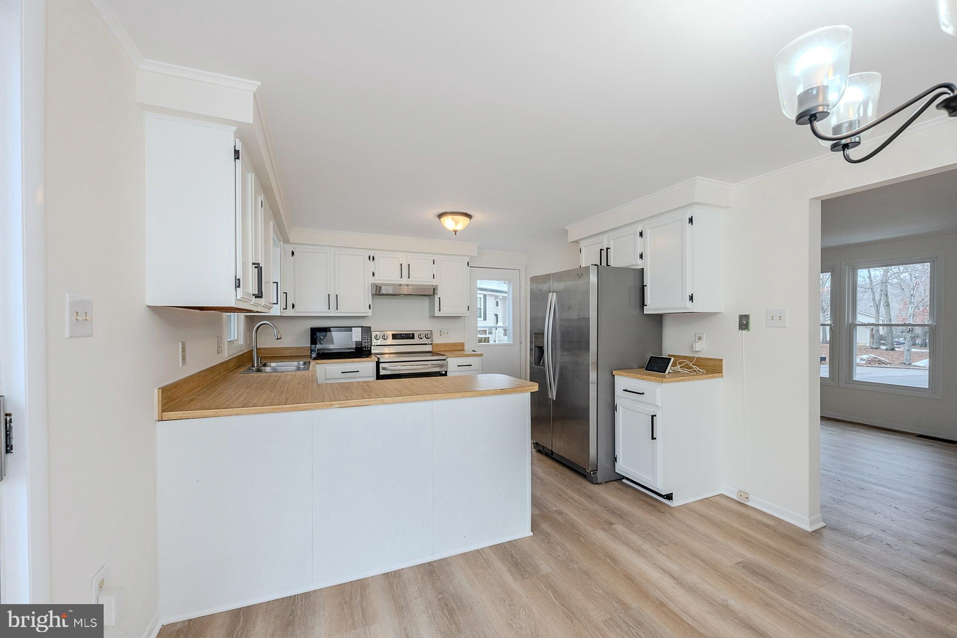 8414 Belding Court Brandywine, MD 20613 - Photo 16 of 37 a kitchen with stainless steel appliances granite countertop a refrigerator a stove top oven a sink dishwasher and white cabinets with wooden floor