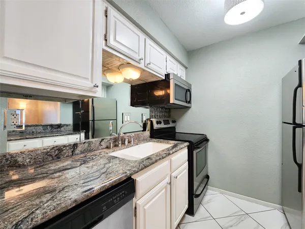 a kitchen with a sink a counter top space cabinets and stainless steel appliances