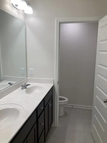 a bathroom with a granite countertop sink a toilet and a mirror