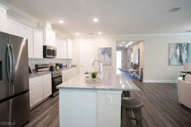 a kitchen with granite countertop kitchen island stainless steel appliances a refrigerator a stove a sink a dining table and chairs