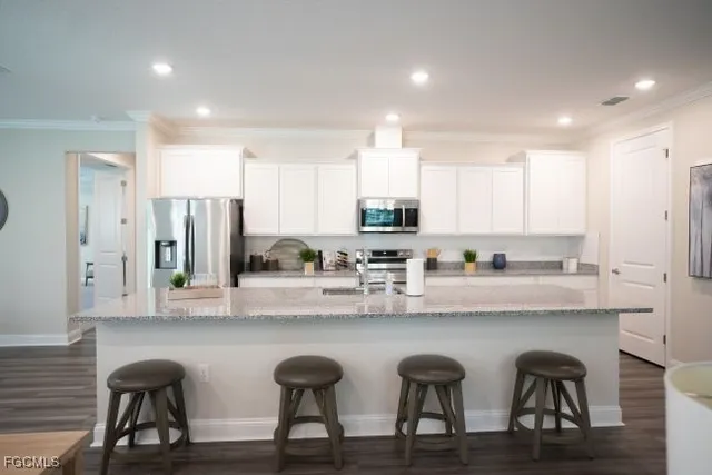 a kitchen with stainless steel appliances granite countertop a table chairs sink refrigerator and cabinets