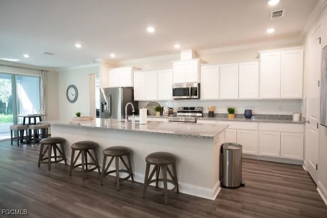 a kitchen with stainless steel appliances granite countertop a table chairs microwave and sink